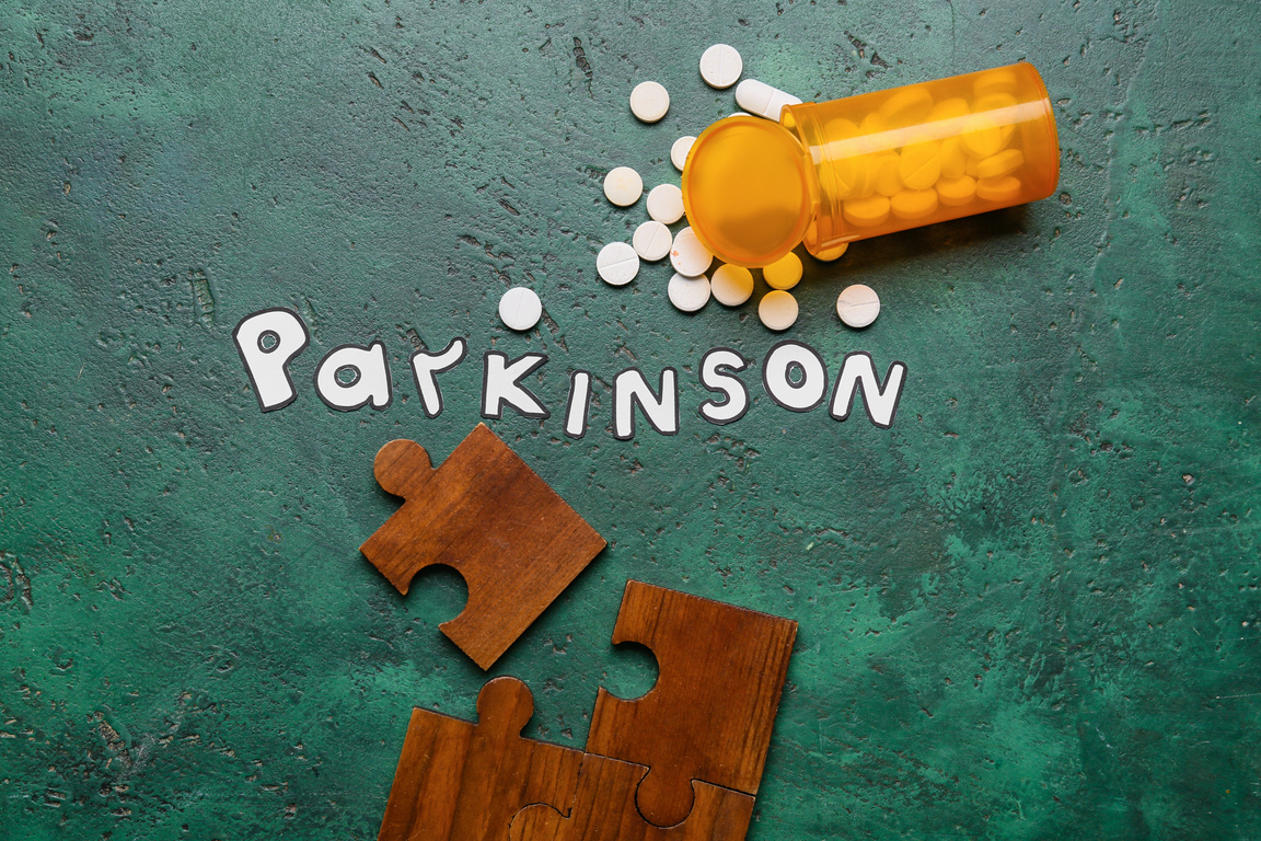 Word PARKINSON with Puzzle Pieces and Pills on Green Background